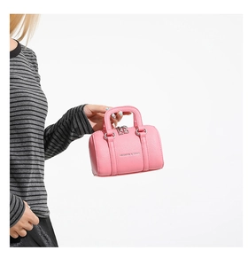 Détail du mini sac polochon rose avec texture cuir grainé et finitions en métal argenté