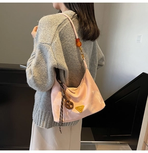 Detailed view of a pink hobo bag featuring a gold metal triangle plate and amber bead strap