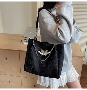 Détail du sac cabas noir avec chaîne papillon argentée et breloques en perles blanches