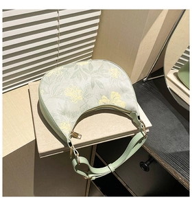 Detail of floral crescent shoulder bag with golden zipper on a gray fabric book