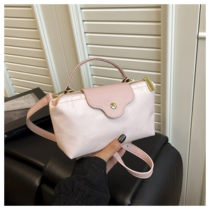 Detail of pink nylon crossbody bag with scalloped leather flap and gold snap button