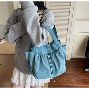 Detailed side view of the blue nylon tote bag with drawstring closure and side pockets