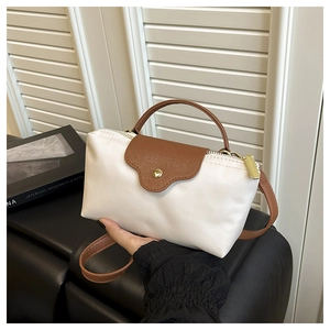 Detail of two-tone nylon and leather crossbody bag with golden zipper and strap