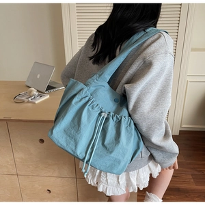 Close-up of sky blue casual drawstring tote bag with snap button and pleated texture