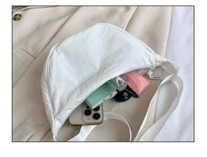 Detail showing white nylon crescent bag interior space with smartphone and notebooks