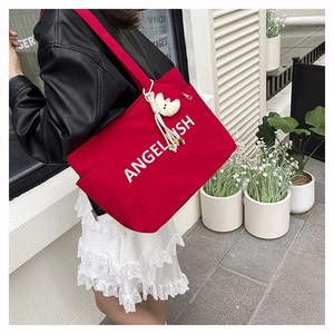 Détail du sac cabas en nylon rouge avec texte blanc et breloque lune en peluche jaune
