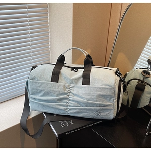 Detail of light blue travel bag with pleated design and detachable shoulder strap