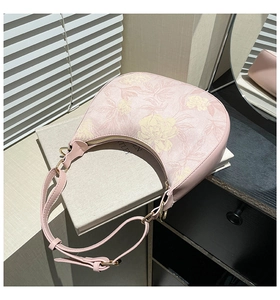 Detail view of pink floral hobo bag with gold hardware on a book for a vintage aesthetic