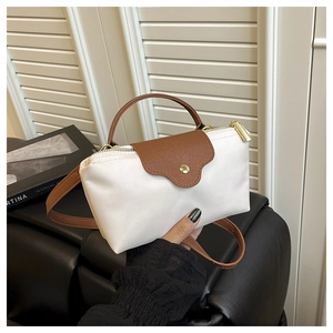 Detail of white nylon dumpling bag with brown leather handles and gold zipper closure