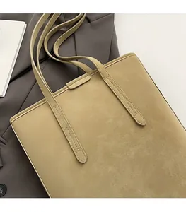 Detailed view of khaki suede bucket bag stitching and slim strap on a gray blazer