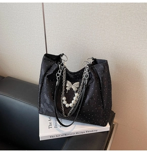 Détail d'un sac cabas noir à pois avec pendentif papillon et bandoulière en perles