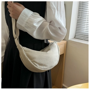 Detail of minimalist beige nylon crescent bag with adjustable shoulder strap and zipper