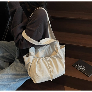 Detail of off-white tote bag featuring drawstring closure and wide comfortable shoulder strap