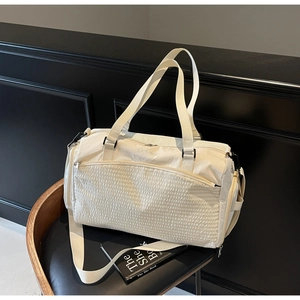 Detail der beigen Reisetasche mit Steppmuster, verstärkten Griffen und Schultergurt