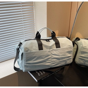 Detail of mint green travel bag with pleated nylon fabric and black woven handles