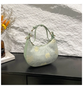 Detailed close-up of light green floral half-moon bag with elegant golden metal hardware