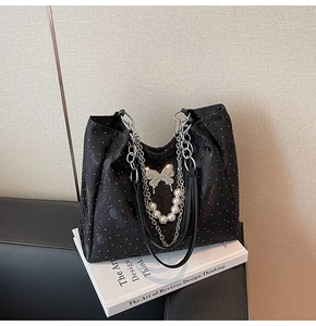 Détail du sac noir avec boucle papillon argentée et bandoulière en perles métal