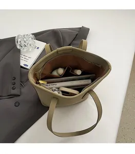 Top view of spacious interior in khaki leather tote bag showing items like books and tablet