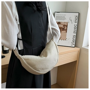 Minimalist beige crescent nylon bag worn by model in a stylish cafe setting