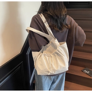 Detail of beige drawstring tote bag showing adjustable side straps and textured fabric