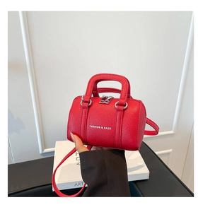 Détail d'un mini sac oreiller rouge avec texture grainée et logo en texte blanc