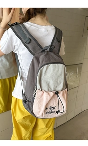 Detail view of the tricolor nylon backpack featuring wide padded straps and a D-ring hook