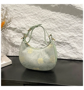 Close-up of floral print handbag with golden metal hardware on a dark wooden surface