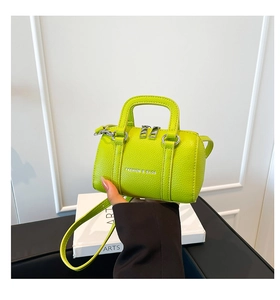 Gros plan d'un mini sac oreiller vert fluo en cuir grainé avec texte mode et poignée