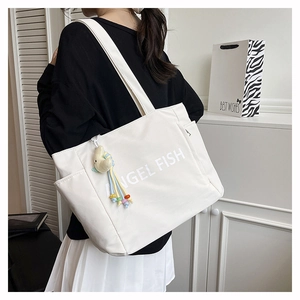 Détail du sac cabas blanc en toile avec texte Angel Fish et breloque lune en peluche