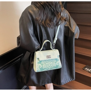 Detail of mint green crossbody bag with floral print and silver twist lock on leather