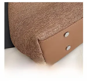 Close-up of brown textured fabric and leather base with silver metal rivets on bag