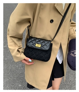 Detail of black quilted flap bag with gold turn-lock and mixed texture on crossbody strap