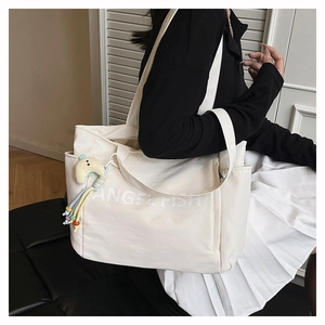 Détail du grand sac cabas en nylon blanc avec texte Angel Fish et charm lune jaune