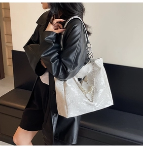 Détail du sac cabas blanc avec broderie papillon, chaînes en métal et perles élégantes