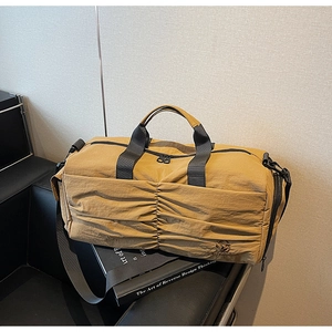Detail of khaki travel duffel bag showing pleated nylon texture and black handles