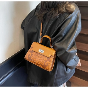 Detail view of caramel brown vintage handbag featuring embossed floral pattern and metal lock