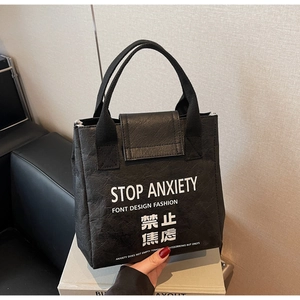 Detail of waterproof Dupont paper bag with white Stop Anxiety slogan and black leather texture