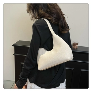 Detail of off-white woven hobo bag showing texture and wide shoulder strap design