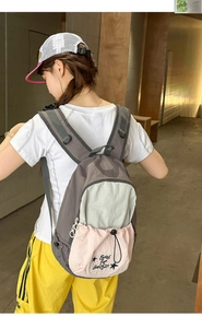 Detail view of the tricolor backpack featuring grey, blue, and pink panels in a casual style