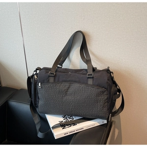 Details der strapazierfähigen schwarzen Reisetasche mit Wollabag-Logo auf Ledersofa
