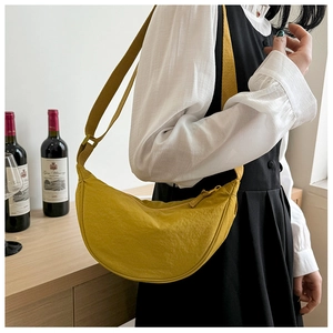 Detail of a bright yellow crescent nylon crossbody bag with adjustable wide shoulder strap