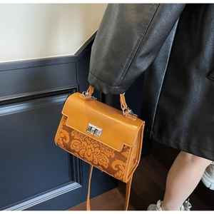 Detail of a vintage orange handbag with floral pattern and silver metal clasp detail