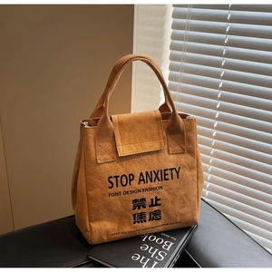 Detail of tan Dupont paper tote with Stop Anxiety slogan and artistic shadow lighting