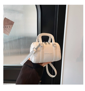 Détail d'un mini sac cylindre blanc à motif litchi avec double fermeture et bandoulière