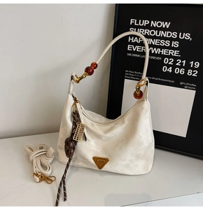Dettaglio borsa sottobraccio in nylon crema con manico in perle ambra e ciondolo oro