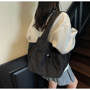 Side view of a black large-capacity tote bag with drawstring pleated detail and wide strap