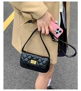 Detail of quilted leather handbag with gold twist lock on shoulder of woman in trench coat