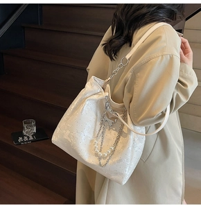 Détail du sac à bandoulière blanc à texture papillon avec chaîne argentée et perles