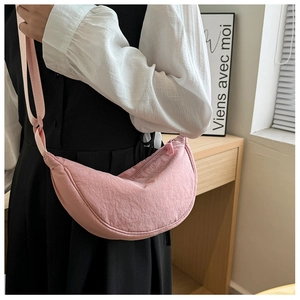 Detail shot of the adjustable fabric strap and durable zipper on the pink nylon crescent bag