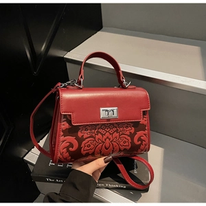 Close-up of red vintage handbag with floral pattern and silver metal twist lock